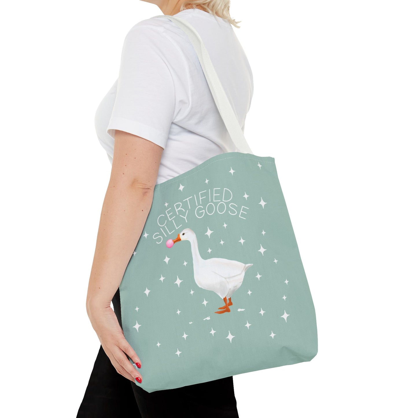 Person holding a tote bag with a goose illustration and text on a light green background