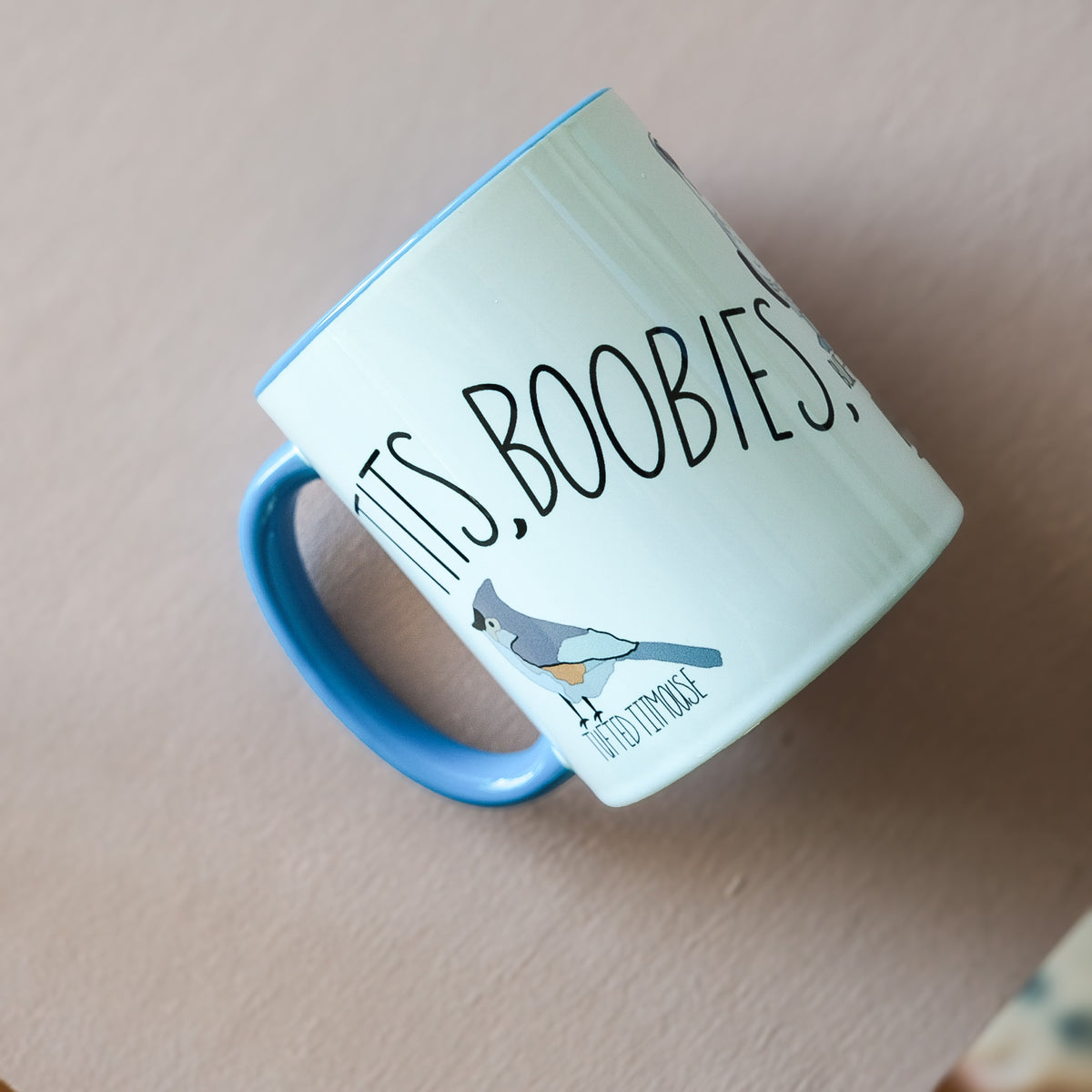 Tits, Boobies & Peckers white ceramic mug with blue handle and bird illustrations.