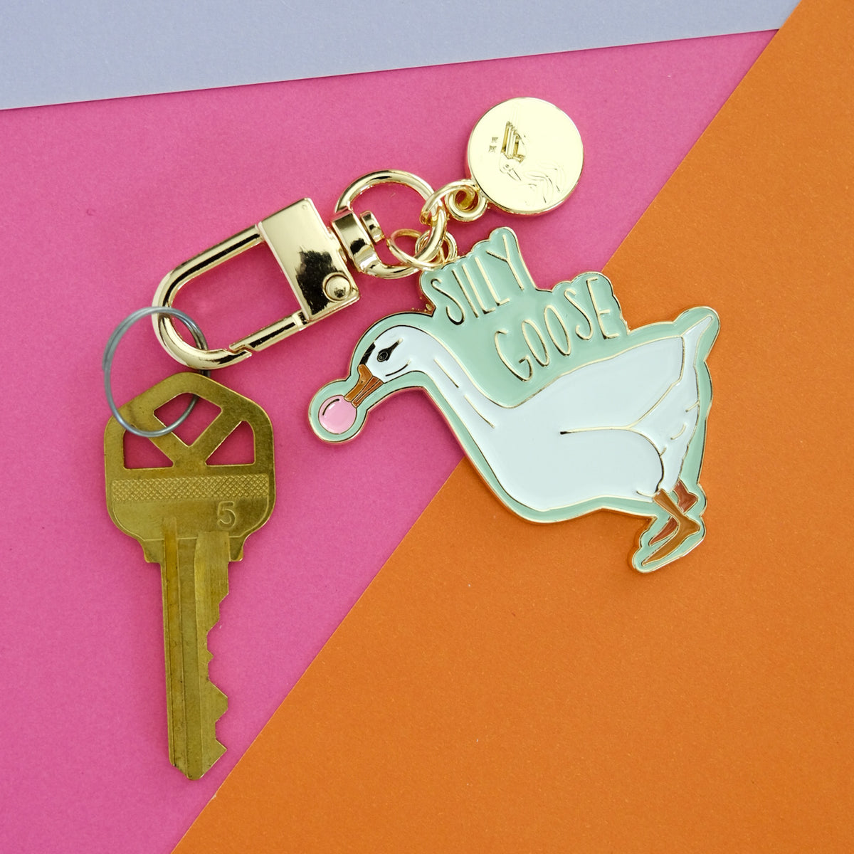 Silly Goose keychain featuring a white goose blowing pink bubblegum, with mint enamel and gold hardware.