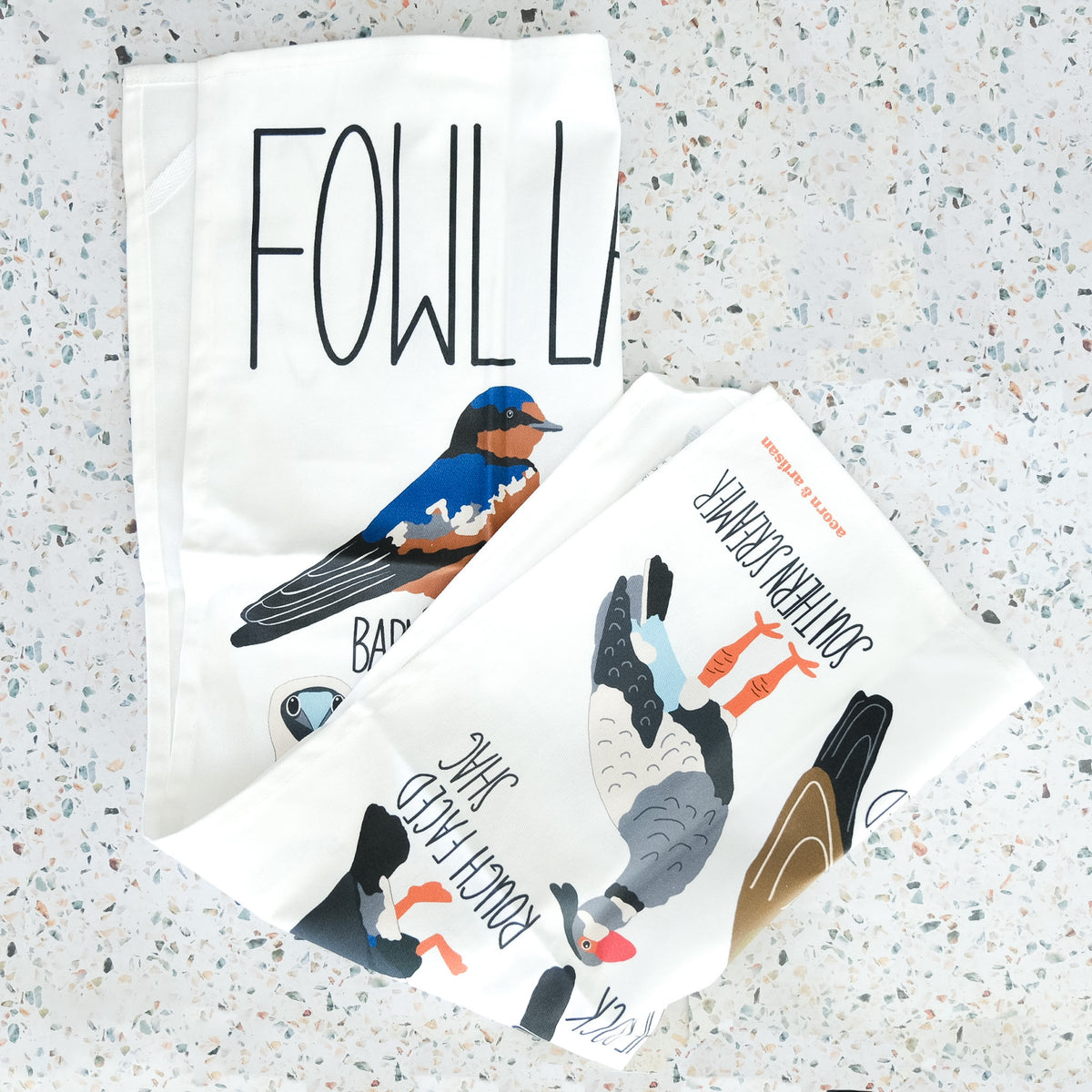 Fowl Language tea towel with illustrated birds and their names displayed with matching pieces.