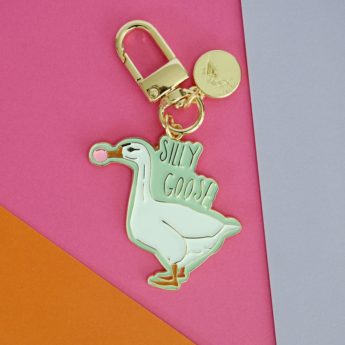 Silly Goose keychain featuring a white goose blowing pink bubblegum, with mint enamel and gold hardware.