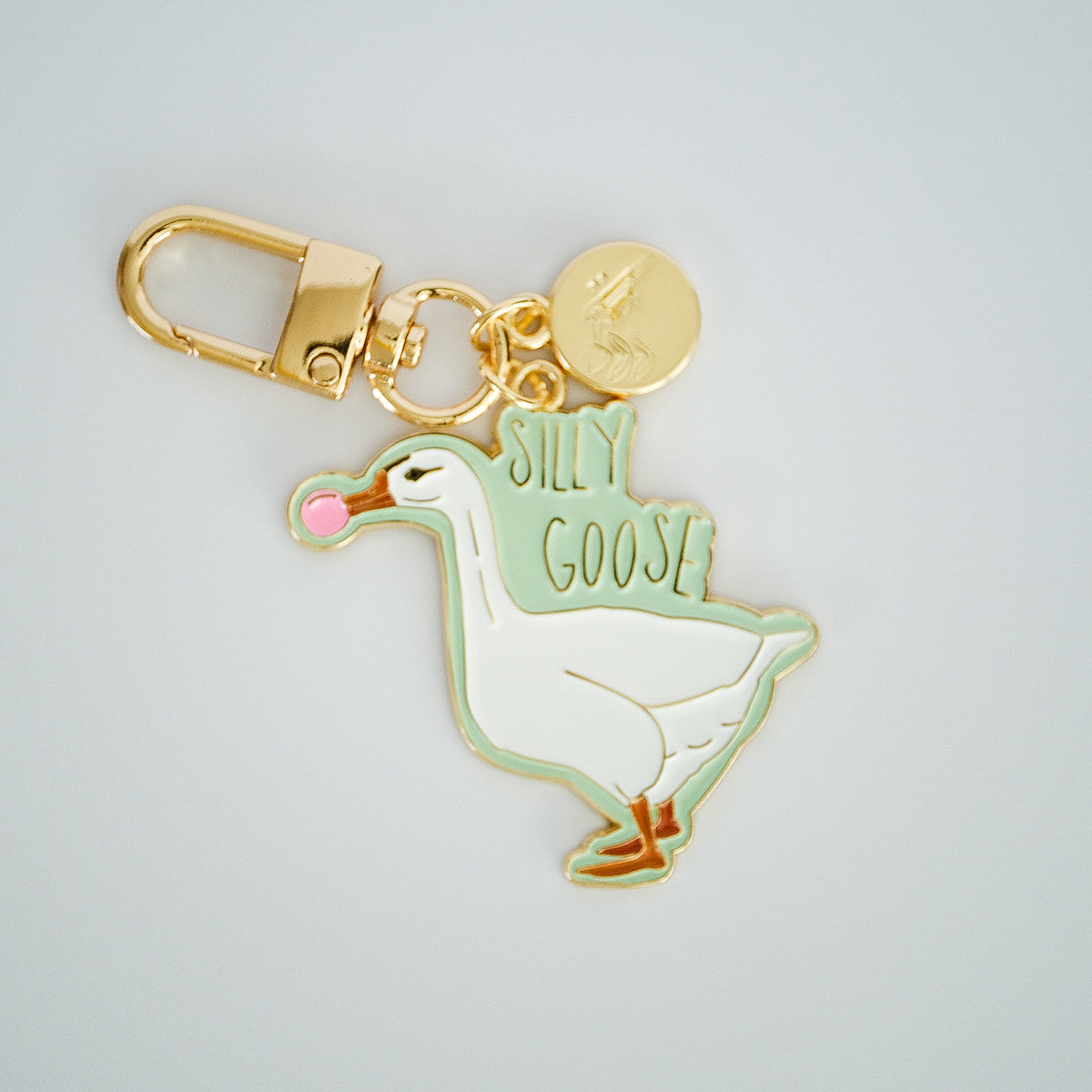Silly Goose keychain featuring a white goose blowing pink bubblegum, with mint enamel and gold hardware.