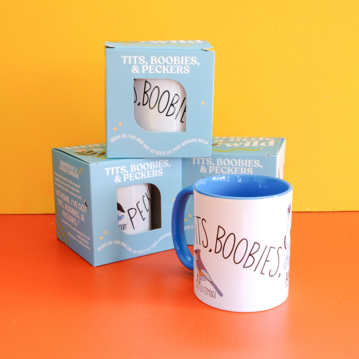 Tits, Boobies & Peckers white ceramic mug with blue handle and bird illustrations.
