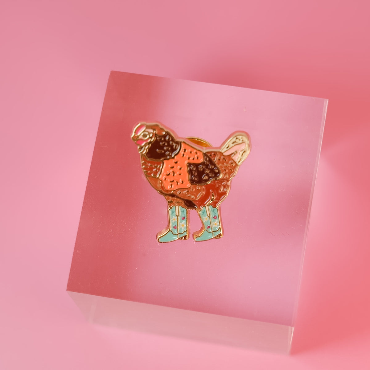 Cowgirl Chicken enamel pin with a chicken in mint strawberry-patterned boots.