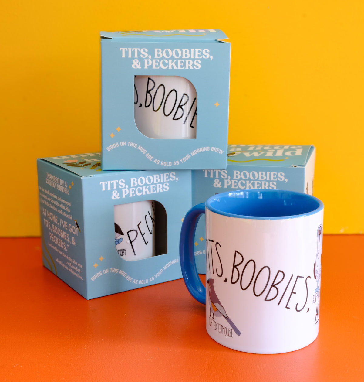 Tits, Boobies & Peckers white ceramic mug with blue handle and bird illustrations.