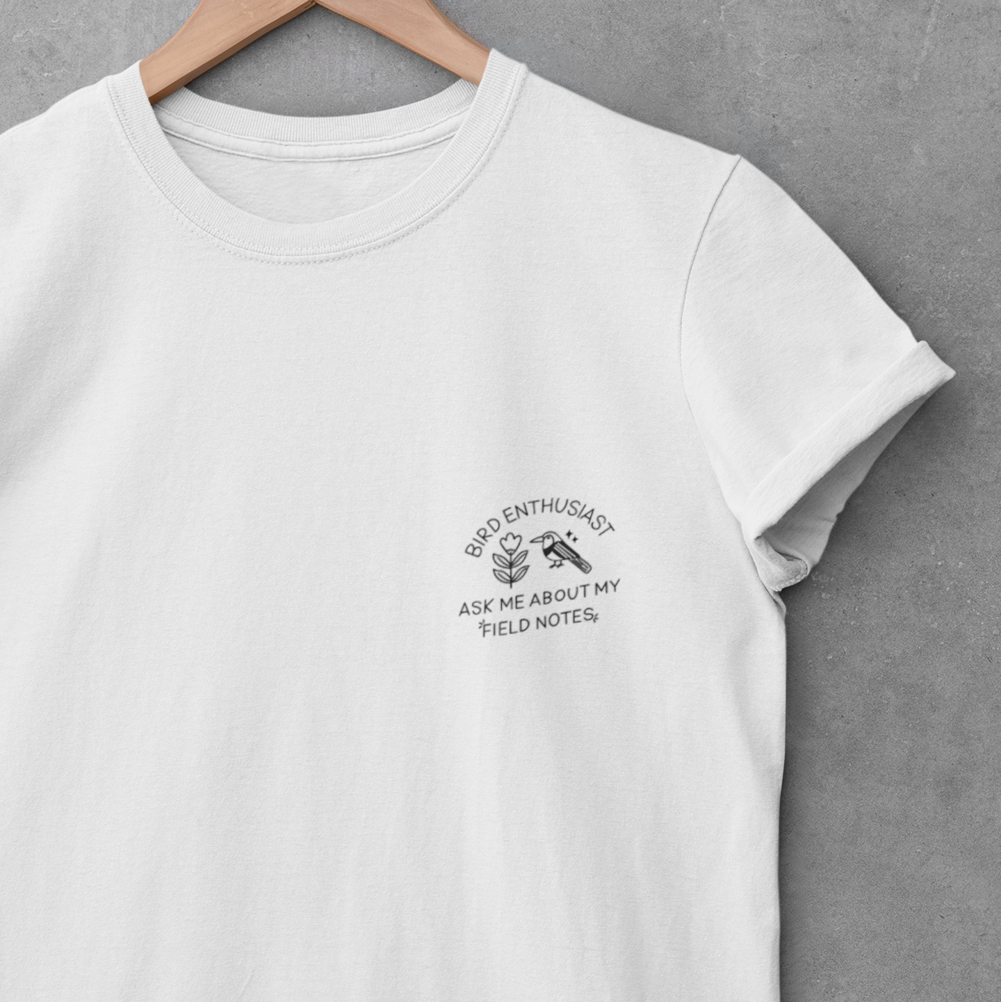 White t-shirt with text and graphic on a hanger against a gray background