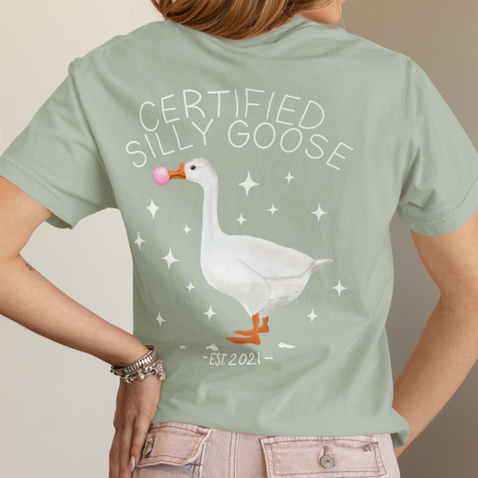 Person wearing a light green t-shirt with a goose graphic and text on the back.