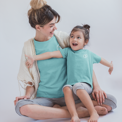 Woman and child sitting together wearing matching teal shirts on a plain background
