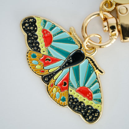 Close-up of Cosmic Moth Enamel Keychain, showing the illustrated design and product details