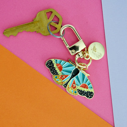 Cosmic Moth Enamel Keychain shown in use