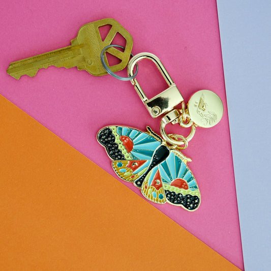 Cosmic Moth Enamel Keychain shown in use