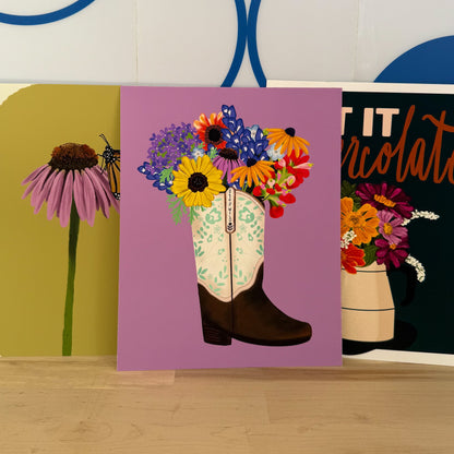 Three art prints with floral designs on a wooden surface.