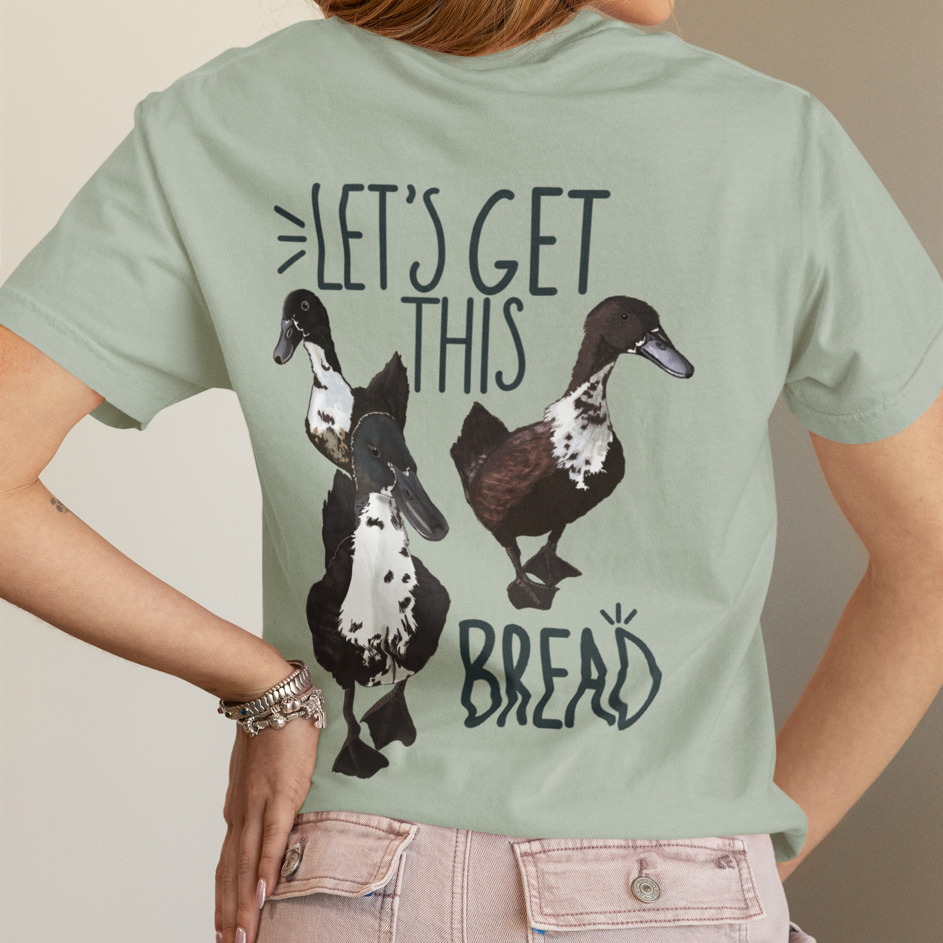 Person wearing a light green t-shirt with duck graphics and text on the back.