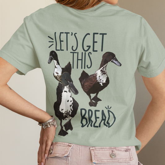 Person wearing a light green t-shirt with duck graphics and text on the back.