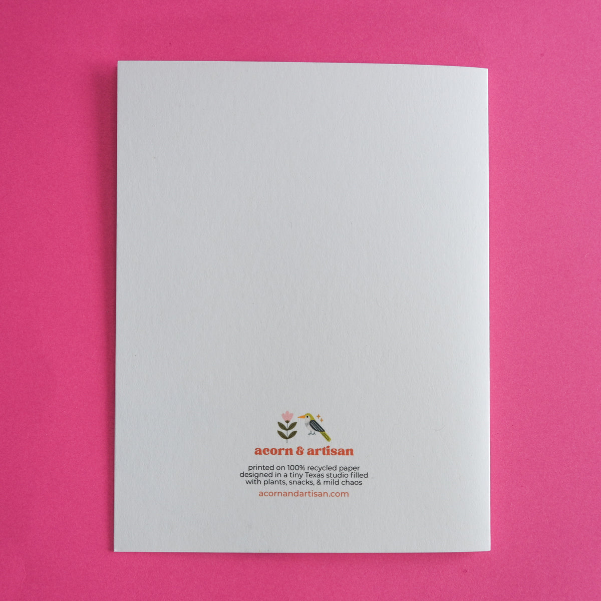 Back of an Acorn & Artisan greeting card with small brand logo and printed product information.